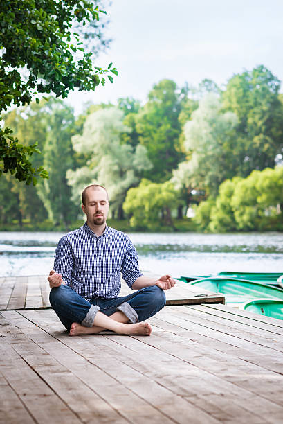 istock Young man with closed eyes relaxing and meditating in morning 176429527