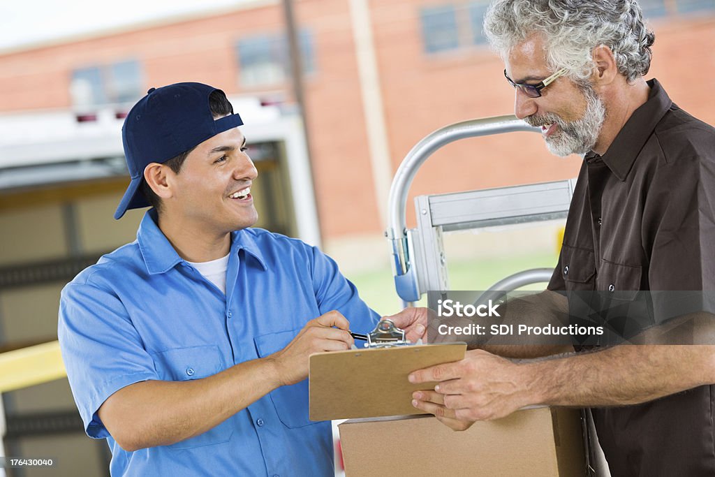 Business owner signing for packages from delivery driver Adult Stock Photo
