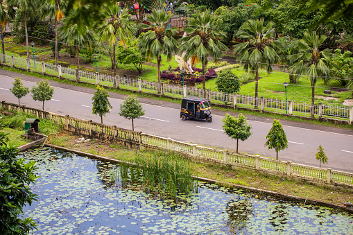 An autorickshaw drives along a road with lush landscape in India (Port Blair)