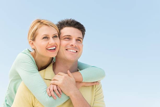 Man From Behind While Looking Away Against Clear Sky Happy young woman man from behind while looking away against clear blue sky cheek to cheek stock pictures, royalty-free photos & images