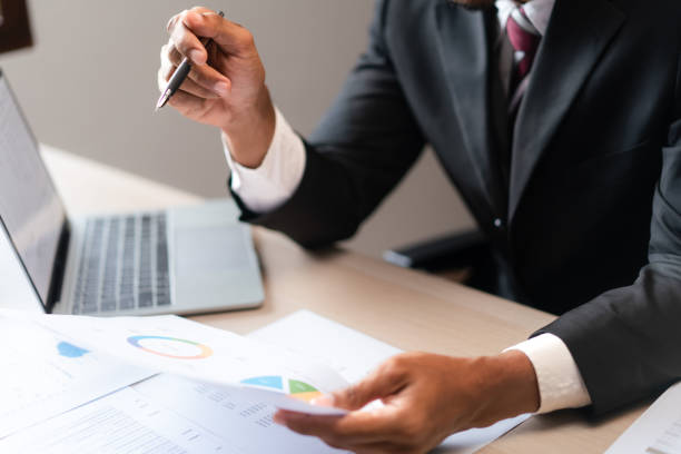 istock Businessman read marketing graph paper and checking data on laptop to analyzing strategy of startup 1764314204