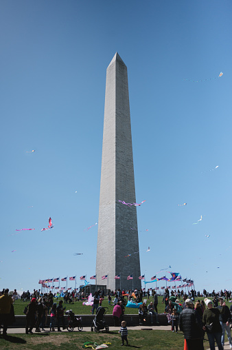 A photo of the Washington Monument in Washington, D.C. surrounded by flying kites and onlookers at the National Kite Festival.