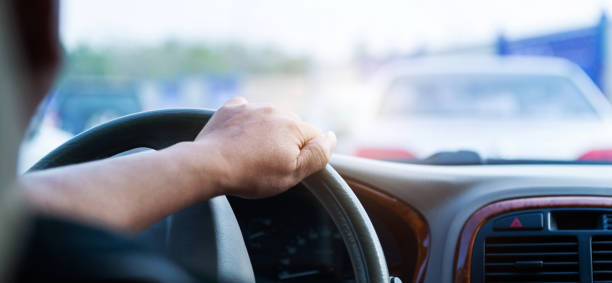 istock Man hand on steering wheel inside of a car at traffic jam 1764317362