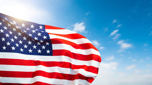 istock American flag waving on blue sky background 1764317895