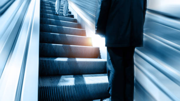 Low section of businessman standing at modern escalator