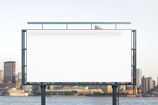 Blank white billboard on city buildings background at daytime, front view. Mockup, advertising concept