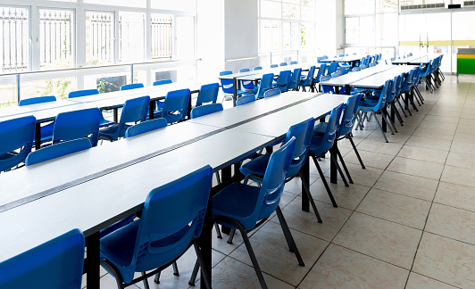 Clean school cafeteria with empty seats and tables