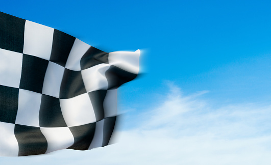 Closeup of checkered flag against blue sky