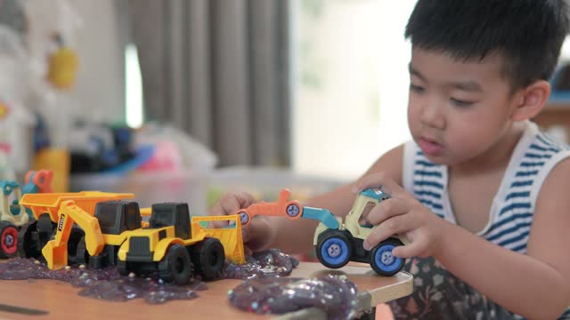 A boy plays with a toy truck in the house.