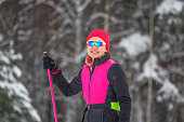 Portrait of a smiling girl skiers dressed in sporty clothes with ski poles in her hand