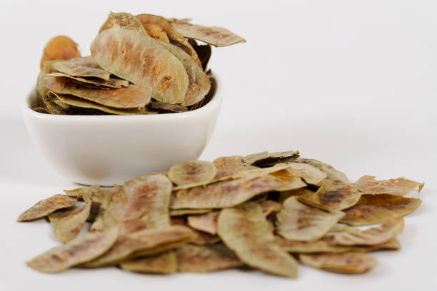 Senna alexandrina pods. Cassia senna, with depurative and detoxifying properties in a white ceramic bowl isolated on a white background.