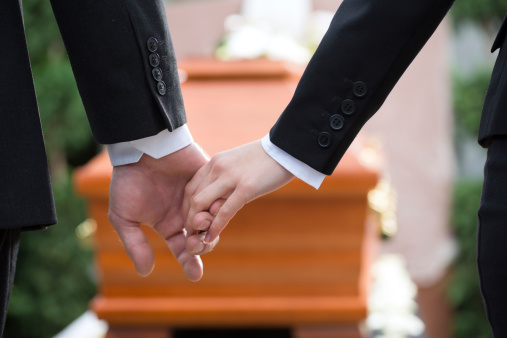 Two people holding hands at a funeral
