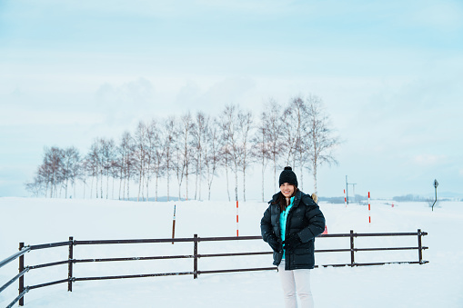 Woman tourist Visiting in Biei, Traveler in Sweater sightseeing view with Snow in winter season. landmark and popular for attractions in Hokkaido, Japan. Travel and Vacation concept