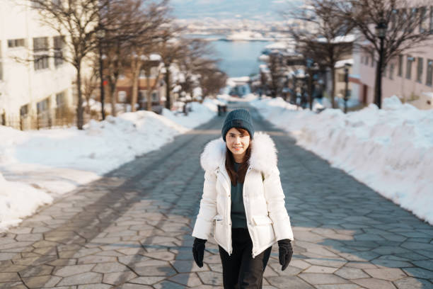 Woman tourist Visiting in Hakodate, Traveler in Sweater sightseeing Hachiman Zaka Slope with Snow in winter. landmark and popular for attractions in Hokkaido, Japan. Travel and Vacation concept Woman tourist Visiting in Hakodate, Traveler in Sweater sightseeing Hachiman Zaka Slope with Snow in winter. landmark and popular for attractions in Hokkaido, Japan. Travel and Vacation concept motomachi kobe stock pictures, royalty-free photos & images