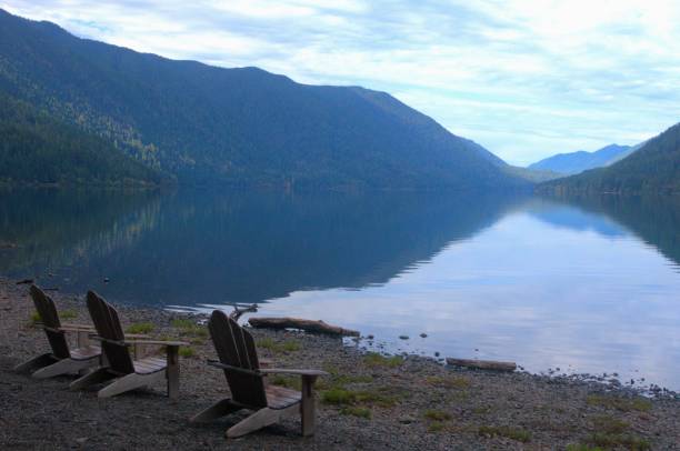 istock Three Adirondack chairs on the beach next to a calm lake 1764416589