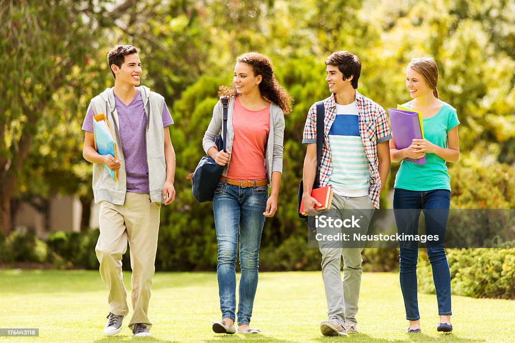 Teenage Students Looking At Friend While Walking On Campus Full length of teenage students looking at friend while walking together on college campus. Horizontal shot. Campus Stock Photo