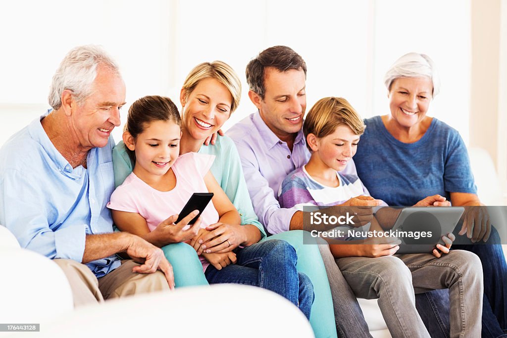 Familia usando tableta Digital y teléfono inteligente en su casa - Foto de stock de Familia multigeneracional libre de derechos