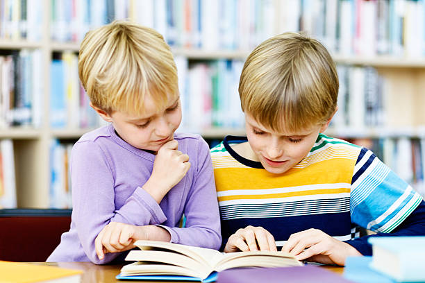 istock Contented brother and sister reading together in library 176444296