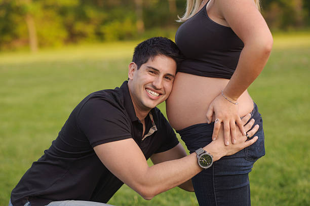 istock Laughing Husband Hugging Wife's Pregnant and Bare Belly 176444647