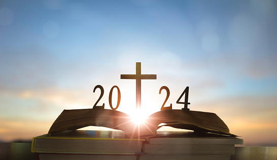 2024 new year and cross of jesus christ on open holy bible with sunrise background