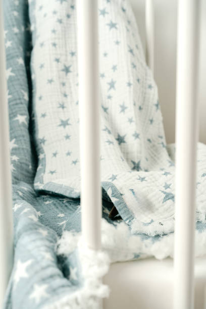 istock Soft blue muslin blanket hanging on a baby's bed 1764488717
