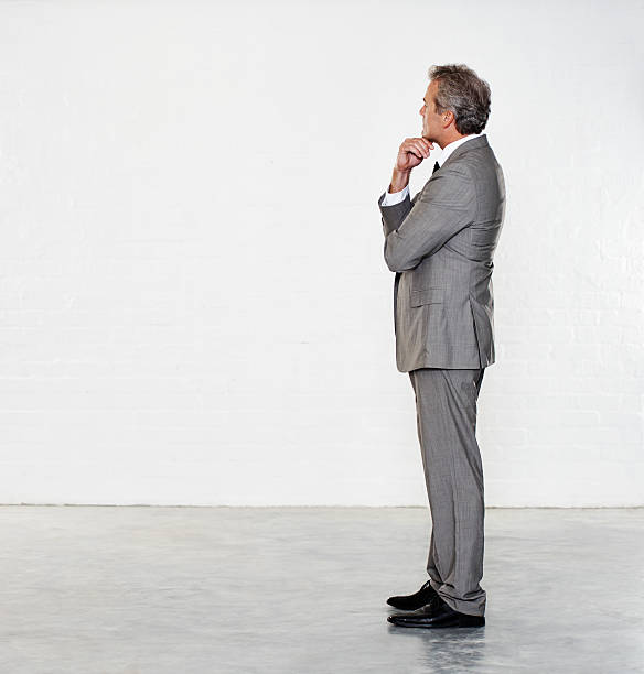 Thinking over his career future Thoughtful mature businessman standing against a white background man standing profile stock pictures, royalty-free photos & images