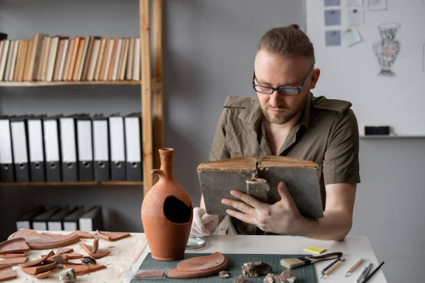 istock Archeologist works in office, reading old professional book, researching discovered ancient civilization cultural artifact 1764500381