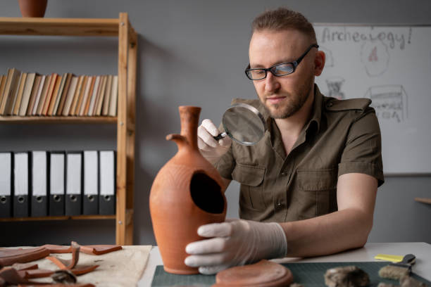 istock Archaeologist working in the office looks at an ancient amphora through a magnifying glass, studies ancient culture 1764500385