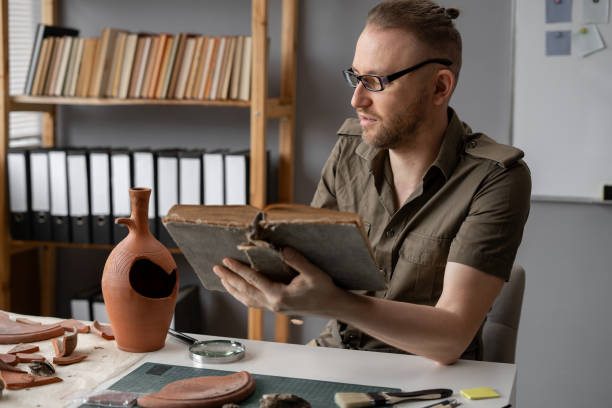 istock Archaeologist working in office reading ancient archaeological book 1764500396