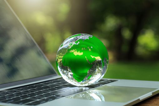 Environmental Technology.Environmental protection, sustainable energy sources. Globe Glass on a laptop with a green background that represents green energy,  and green technology for saving energy.