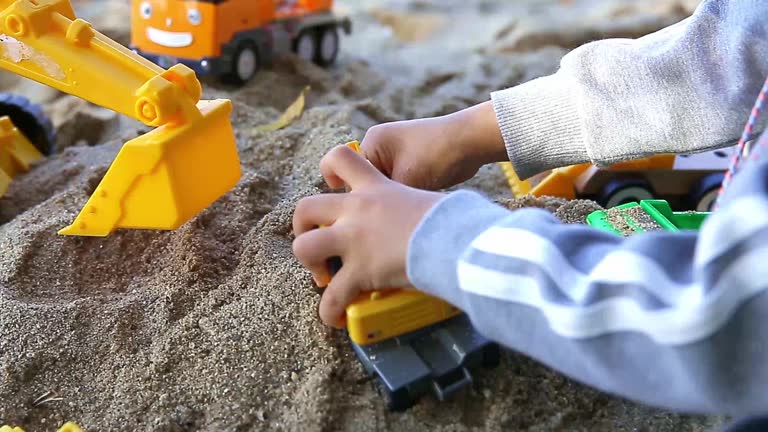 a child's hand playing sand with a toy