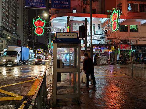 People on the sidewalks at night by two pawnshop neon signs on Hennessy road, a main street in Wan Chai district, Hong Kong island.