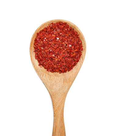 top view flat lay dry red pepper flake powder coarse. Korean chili ground Gochugaru. Korean red pepper flake powder coarse ground gochugaru in wood spoon isolated on white background