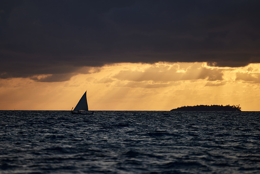 View of the sailboat floating on the sea at sunset.