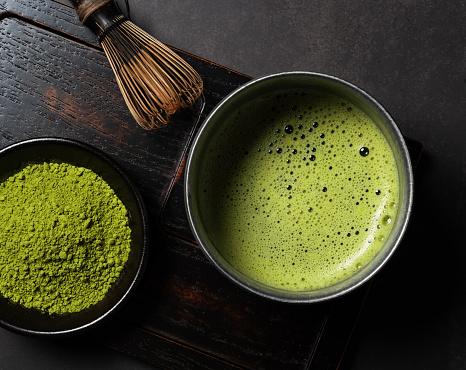 Matcha powder and green tea on dark background. Chasen (tea whisk). View from above.
