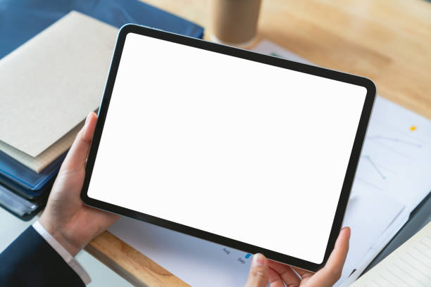 istock Businessman hand holding digital tablet with blank screen for graphic display montage on the desk in office. 1764574750