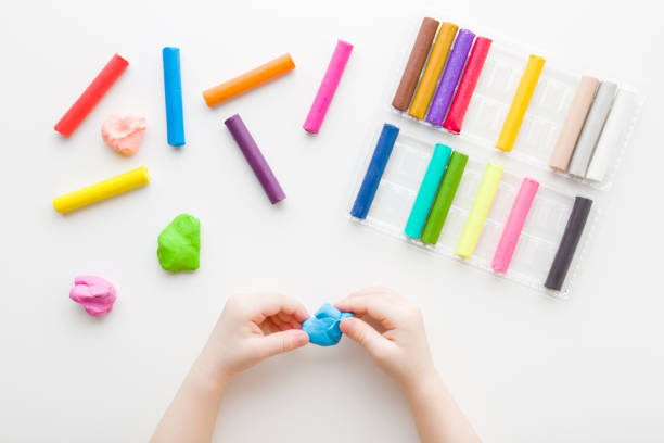 istock Baby hands holding and kneading blue modeling clay on white table background. Closeup. Point of view shot. Toddler development. Preparing material for making different colorful shapes. Top down view. 1764605215