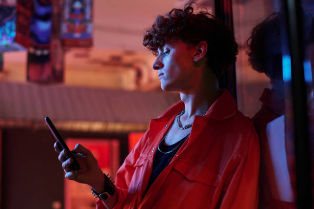 istock Guy with curly hair in stylish attire looking at smartphone screen 1764637992