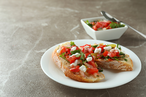 Plate with bruschetta snacks on gray textured table