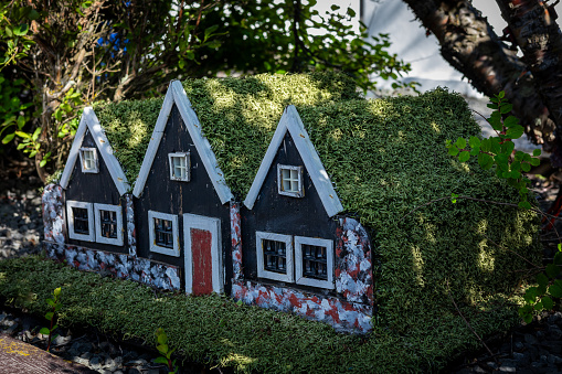 Three small black toy wooden elf homes, typical decoration in the gardens in Iceland.