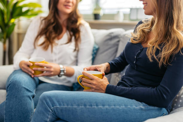 istock Two Female Friends Drinking Coffee While Sitting On The Sofa At Home 1764677903