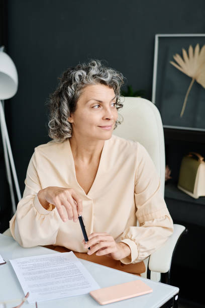 istock Smiling mature female boss thinking of something and looking aside 1764680189