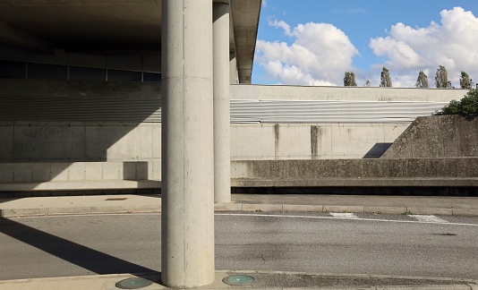Exit of a road underpass with large columns on forground,  concrete block wall  and blue cloudy sky on behind. Background for copy space.