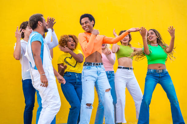 giovani con vestiti colorati che ballano insieme all'aperto - eclectic community foto e immagini stock
