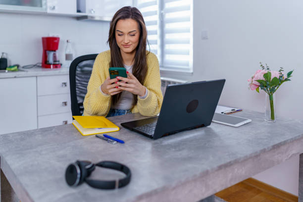 istock Young female student scrolling through social media on her phone, while sitting at her kitchen table 1764694085