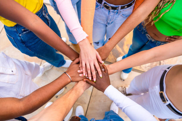 istock Multi-ethnic young people joining hands in a huddle 1764718806