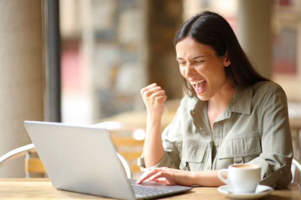 istock Excited woman celebrating in a restaurant checking laptop 1764722155