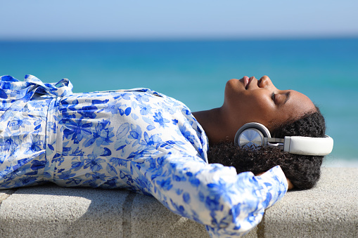 Black woman relaxing listening music on the beach