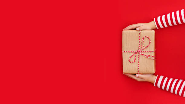 istock gift box in children's hands on a red background, presenting a gift, christmas background 1764730346