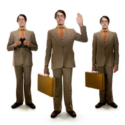 Parody of retro businessman with briefcase waving at camera. There are two other figures with a soft focus, one just holding a brief case and the other with binoculars